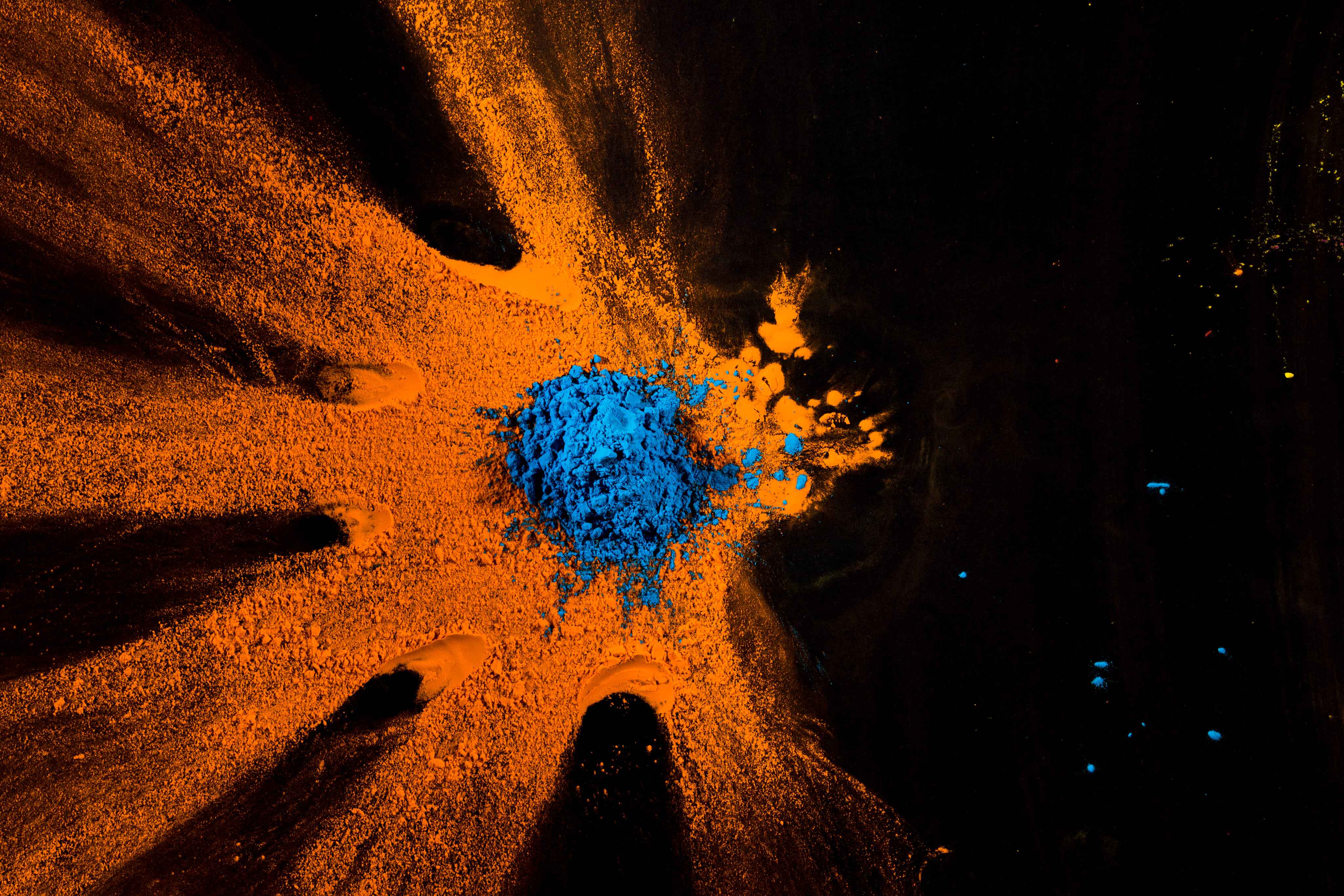 Hands gathered around vivid orange and blue pigment